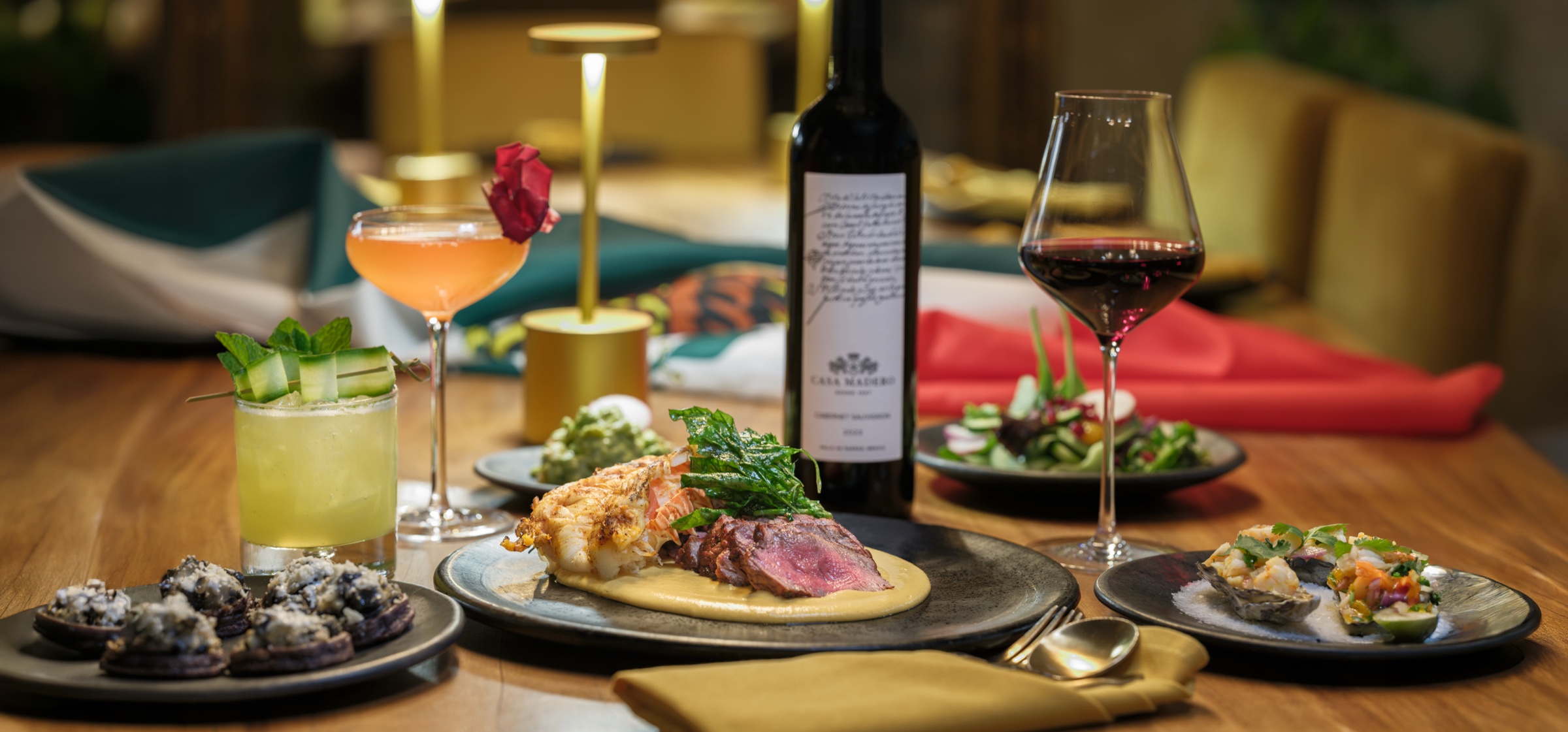 Restaurant table setting with lobster, steak, cocktails and wine — photography by Manny Espinoza